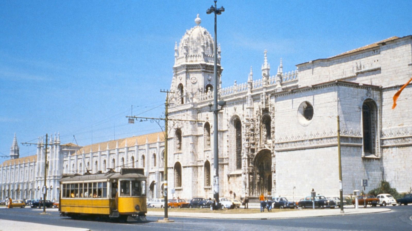 A yellow tram passing the Jerónimos Monastery in Belém